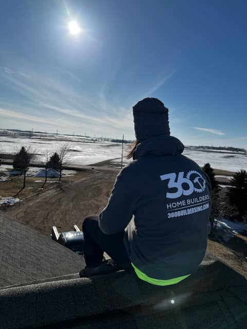 Roofing contractor sitting on top of roof
